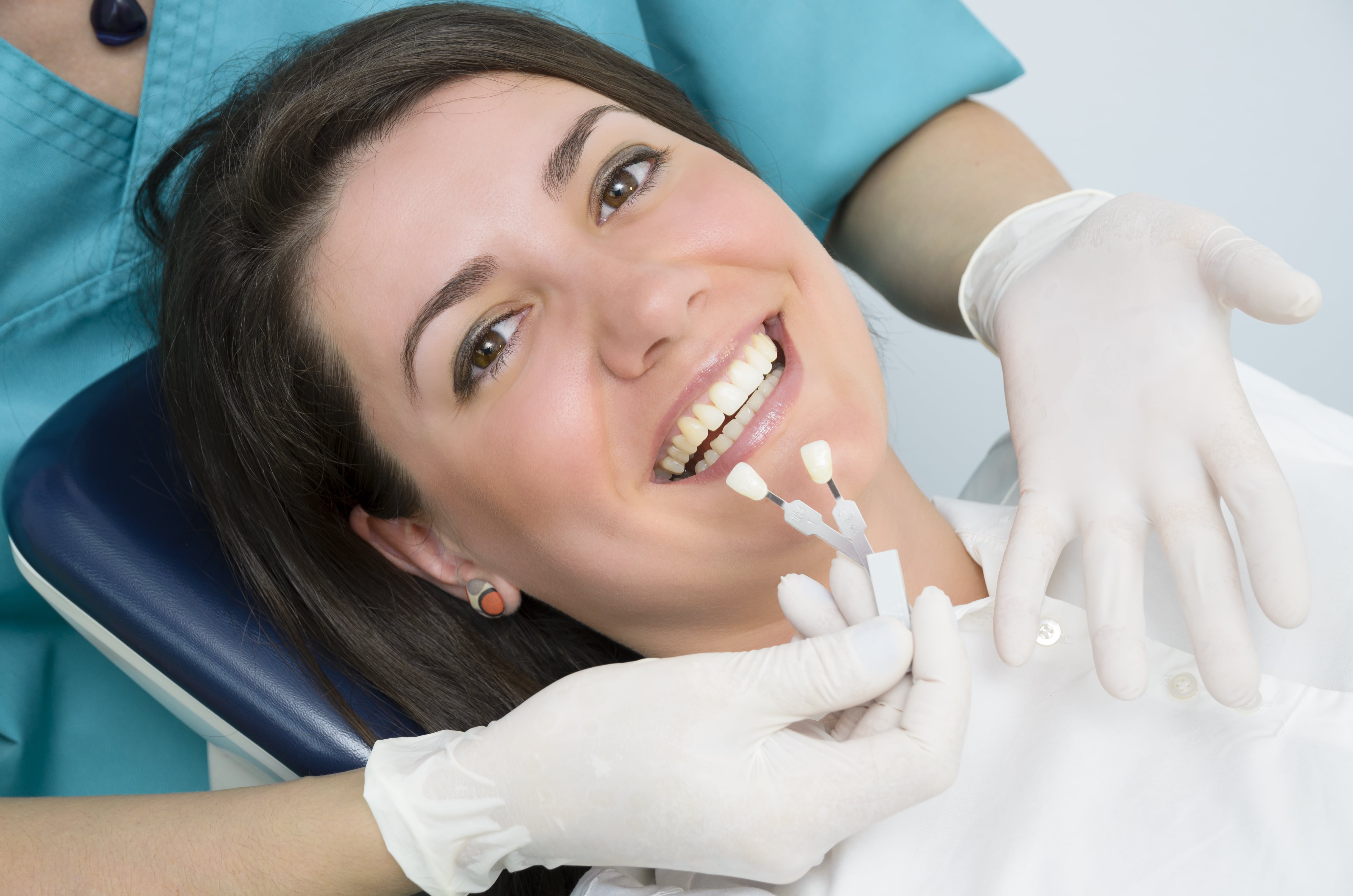 Woman sitting in a dental chair getting her teeth matched for whitening
